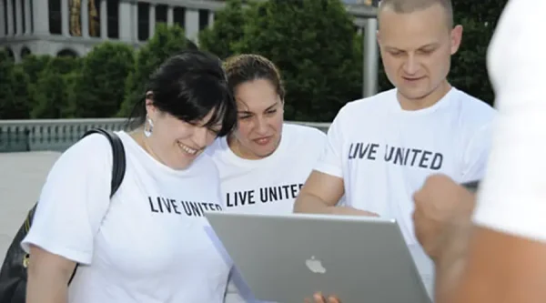 United Way volunteers working together on a computer to manage digital programs